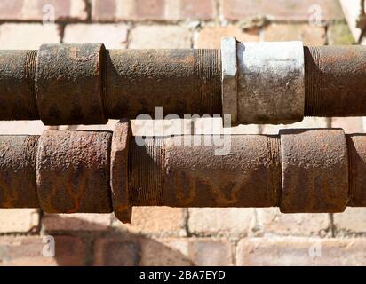 Rusty pipes in front of a brick wall Stock Photo