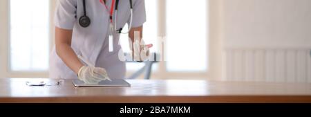 Close up view of female doctor writing blood tests on digital tablet while standing in examination room Stock Photo