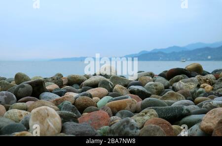 Closeup of Pebble Stones on the Beach with Blurry Seascape in the Backdrop Stock Photo