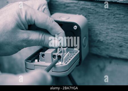 Man wiring an electric socket using an electrical screwdriver outdoor outside.  With colour toning Stock Photo