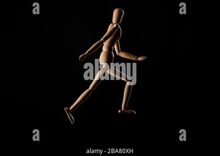 Wooden doll imitating running isolated on black Stock Photo