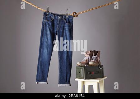 A blue jeans hanging on a rope with a pair of boots on top of a bullet box Stock Photo