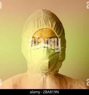 Woman in mask and protective suit, protection concept, close-up, yellow toning. Stock Photo