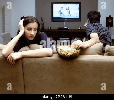 Self-isolation in a quarantine house of a young couple during a coronavirus pandemic. A man and a girl are watching TV. Stock Photo