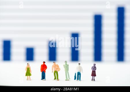 Selective focus of people figures on white surface with infographics at background, concept of equality Stock Photo
