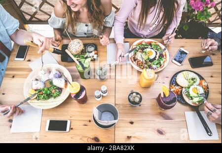 Young people eating brunch and drinking smoothie bowl at vintage bar - Happy people having a healthy lunch and chatting in trendy restaurant - Food tr Stock Photo