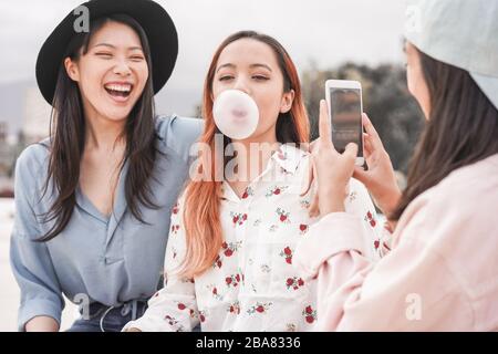 Happy asian girls making video story for social network app outdoor - Young women friends having fun making live feed - New technology trends and frie Stock Photo