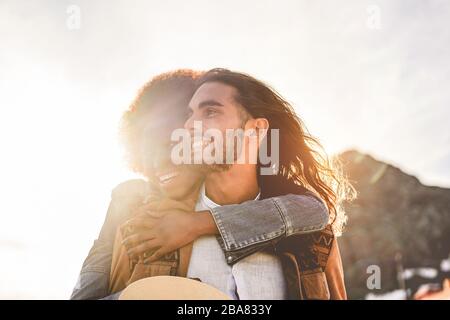Happy couple having tender moments outdoor at sunset - Young lovers having fun together - Love, relationship and muti ethnic concept - Focus on man