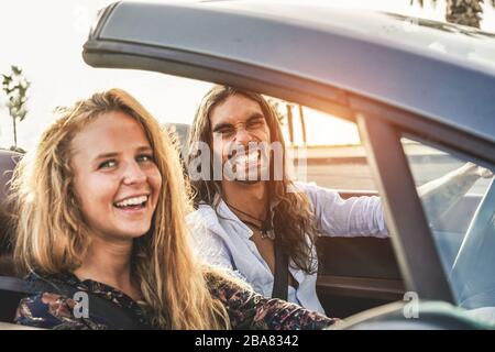 Happy young couple having fun inside convertible sport car - Travel people doing road trip in tropical place - Vacation, journey and relationship conc Stock Photo