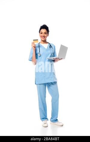 Full length view of african american nurse with stethoscope holding laptop and showing credit card on white background Stock Photo