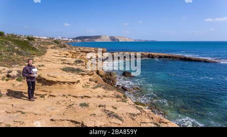 A male pilot on the shore controls a remote control for a drone. While shooting a photo video. Stock Photo