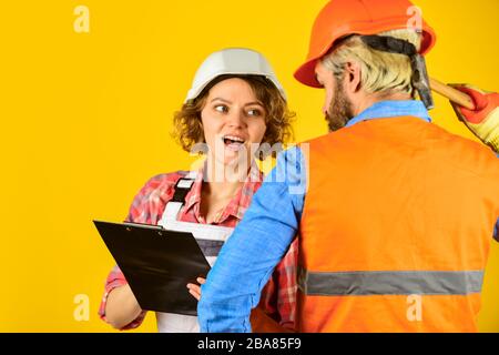 Control process. Renovation concept. Discussing renovation with contractor. Couple planning changes renovation apartment. Woman and man safety hard hat. Redevelopment of home. Couple look documents. Stock Photo