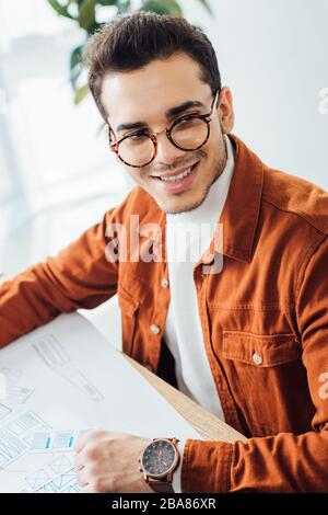 Smiling developer looking away while planning user experience design at table in office Stock Photo