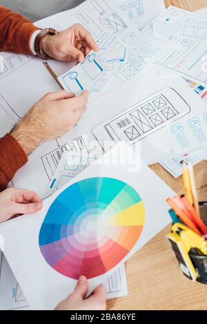 Cropped view of designers working with templates of ux design and color circle on table Stock Photo