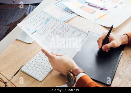 Cropped view of designer planning ux interface of website and using graphics tablet and laptop on table Stock Photo