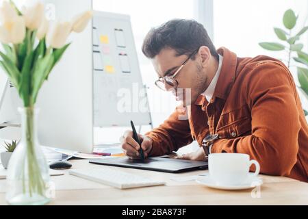 Side view of ux designer working with computer and graphics tablet at table in office Stock Photo