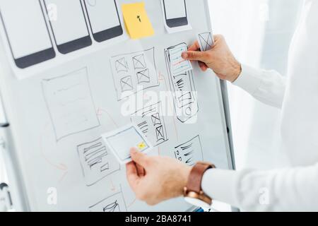 Cropped view of ux designer using layouts while creative app interface on whiteboard Stock Photo