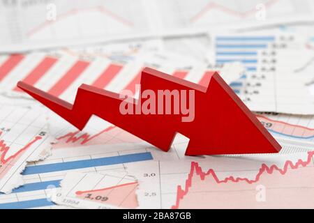 Financial crisis concept with falling red arrow on financial charts from newspapers Stock Photo