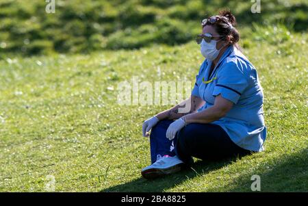 Care worker Carla Martin takes a break from her work and sits on the grass in Sefton Park, Liverpool after Prime Minister Boris Johnson has put the UK in lockdown to help curb the spread of the coronavirus. PA Photo. Picture date: Thursday March 26, 2020. The UK's coronavirus death toll reached 463 on Wednesday. See PA story HEALTH Coronavirus. Photo credit should read: Peter Byrne/PA Wire Stock Photo