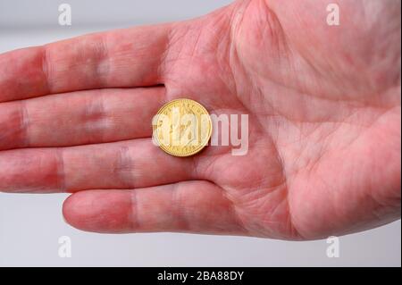 Spanish gold one (una)peseta coin change in the hand from shopping Stock Photo