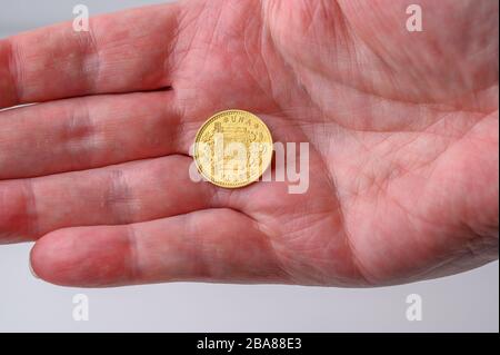 Spanish gold one (una)peseta coin reverse side change in the hand from shopping Stock Photo