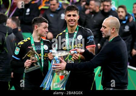 Manchester City's Phil Foden (left), Rodri and manager Pep Guardiola hold the Carabao Cup trophy after winning the Carabao Cup Final at Wembley Stadium, London. Stock Photo