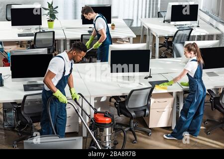 team of young multicultural cleaners working in modern open space office Stock Photo