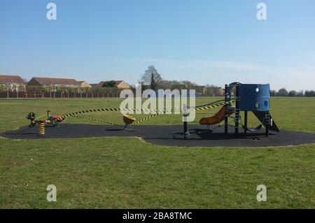 A closed playground covered by hazard warning tape to prevent during the coronavirus pandemic March 2020. Stock Photo