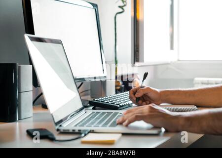 Person working from home at their desk with computers Stock Photo