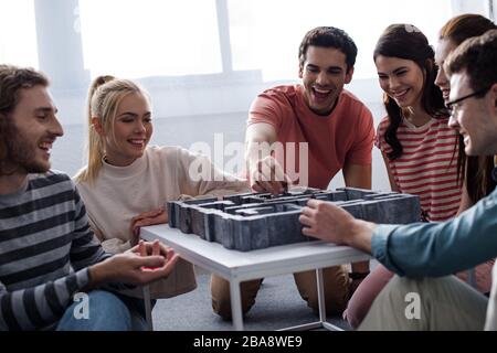 KYIV, UKRAINE - JANUARY 27, 2020: cheerful friends playing labyrinth board game at home Stock Photo