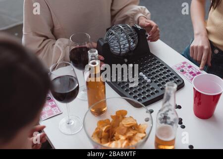 KYIV, UKRAINE - JANUARY 27, 2020: cropped view of girl using lotto balls dispenser near friends Stock Photo