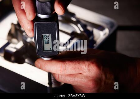 Close-up of a worker checking the deep of drilled hole with a depth gauge in a workshop Stock Photo