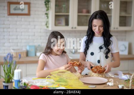 Mom and her cute daughter looking busy in the kitchen Stock Photo