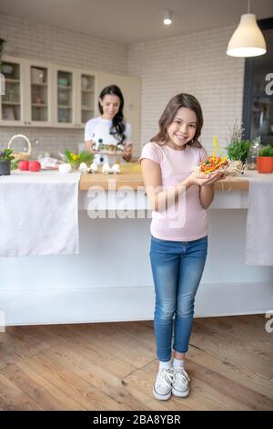 Girl in jeans standing in the kitchen and holding easter bun in her hands Stock Photo