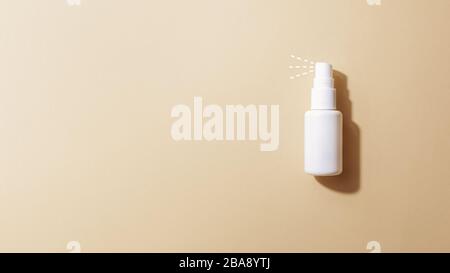 Small alcohol-based disinfecting antiseptic bottle spray spraying on beige background. Personal hygiene, disinfection, coronavirus protection concept Stock Photo