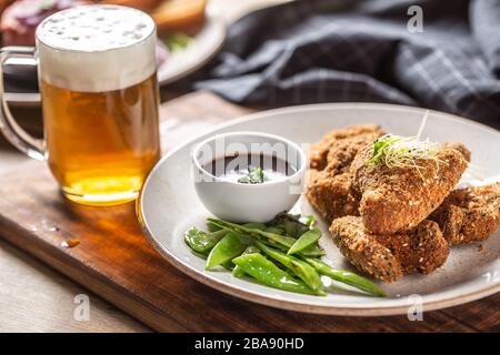 Fried chicken wings with sugar peas herbs and draft beer Stock Photo