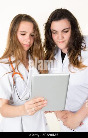 Two women doctor holding tablet with coronavirus positive test concept in front of medical team and patient Stock Photo