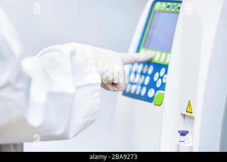 Close up view of laboratory equipment. Blood contaminated by Coronavirus and a sample of it being analyzed . Stock Photo