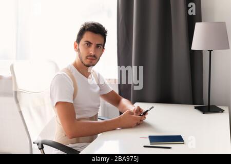 Young man wearing a back support belt. Lumbar brace, back support for back trauma or muscle back strain. Stock Photo