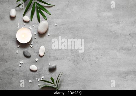 Spa concept on stone background, palm leaves, candle and zen, grey stones, top view, copy space Stock Photo