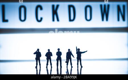 Lockdown concept images - Low key blue tint miniature toy figures of security forces - silhouette of army or police forces. Stock Photo