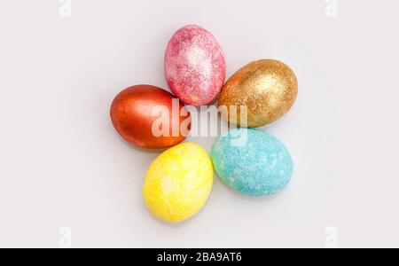 Pelamourous shiny, multi-colored Easter eggs on a white background. Golden egg. Happy Easter. Place for text. Flat lay. Top view. Stock Photo