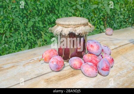 Fruits with leaves. Bowl of plum jam and fresh plums on wooden table Stock Photo