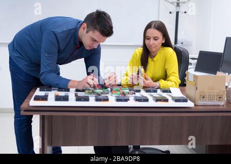 Two young handsome engineers working on electronics components.Tech tests electronic equipment in service center. Technologically Advanced Scientific Stock Photo