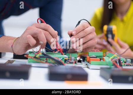 Two young handsome engineers working on electronics components.Tech tests electronic equipment in service center. Technologically Advanced Scientific Stock Photo