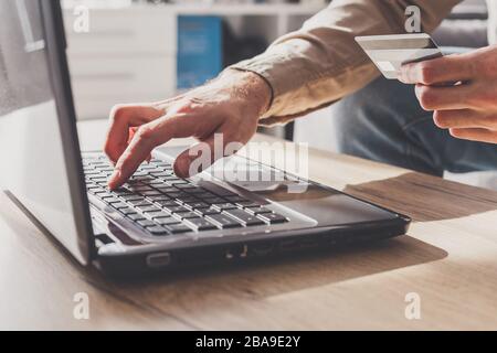 Man enters his bank card details to pay online or other financial transactions Stock Photo
