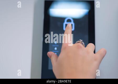 Young businesswoman entering access code at building entrance. The smart home system with access control for entering a PIN code. A hand is typing a c Stock Photo
