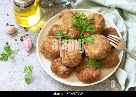 Homemade juicy delicious meat cutlets in plate, meatballs from minced meat on a gray stone table. Stock Photo