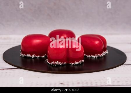 Close-up of mousse cake with red mirror glaze. Cooking french dessert. Frozen mirror icing on the cake. Baking and confectionery concept. Stock Photo