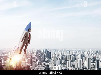 Business person in aviator hat flying on rocket Stock Photo